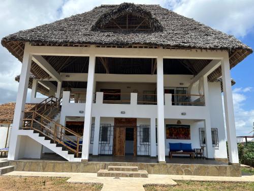 瓦塔穆Nyumbani Tamu的一座带茅草屋顶的大型白色房屋