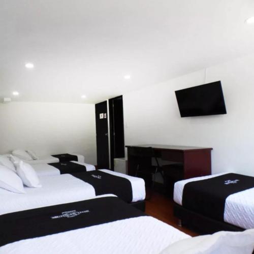波哥大Hotel Colonial Internacional的客房设有三张床、一张桌子和一台电视。