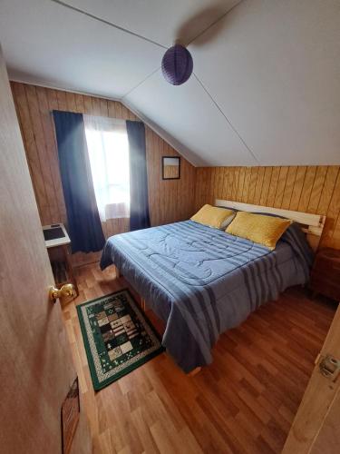 延基韦Cabaña puerto varas的一间卧室配有一张带蓝色床单的床和一扇窗户。