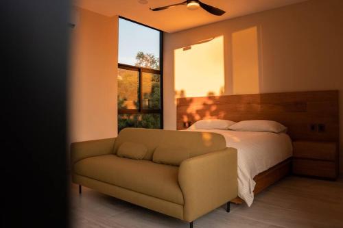 埃斯孔迪多港Casa Amelia Puerto Escondido的一间卧室配有一张床、一张沙发和一个窗口