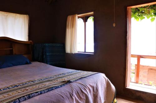 HuillanopampaBLUE SKY Lodge Taquile的一间卧室设有一张床和两个窗户。