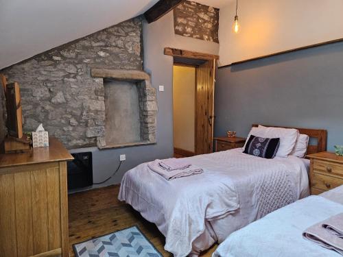 巴克斯顿Rose Cottage - Cosy cottage in Millers Dale的一间卧室设有两张床和石墙