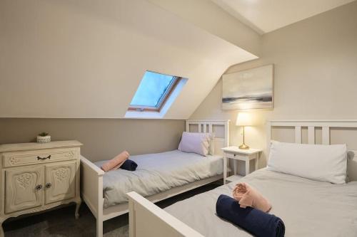 ManorStradbroke House - 5-Bed Home, Sleeps 11, Great for Group Stays & Workers, FREE Parking & Netflix的一间卧室设有两张床和窗户。