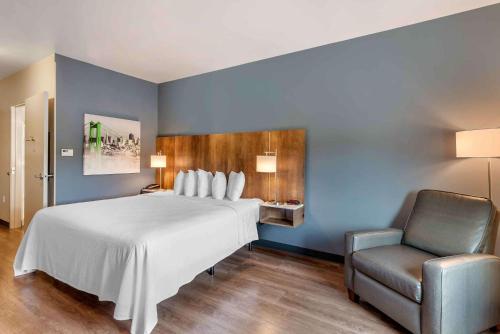 West MelbourneExtended Stay America Premier Suites - Melbourne - I-95的卧室配有一张白色大床和一把椅子