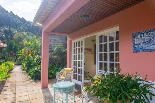圣维森特Madeira Surf Lodge的粉红色房子的门廊,配有桌椅