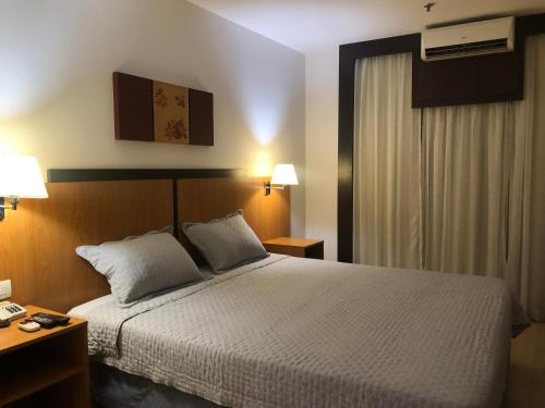 巴西利亚Flat 315 - Comfort Hotel Taguatinga的一间卧室配有一张床、两盏灯和一个窗户。
