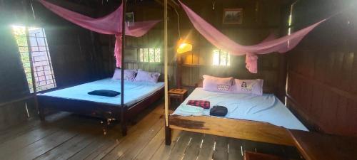 邦隆Tree Trails Homestay & Offers Jungle Trekk-Scooter For Rental的一间卧室配有两张床和蚊帐