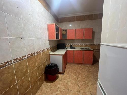 Al ‘AwālīCoov AlAnbarya的一间小厨房,配有红色橱柜和白色冰箱