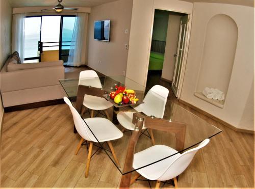 曼萨尼约Hotel Marina Puerto Dorado - Todo Incluido的一间设有玻璃桌和白色椅子的用餐室