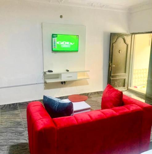 AjaCosy studio apartment的客厅设有一张红色沙发,配有电视