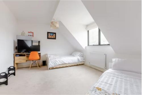 KentChic DuoRooms with Modern Comfort for Families的白色卧室配有一张床和一张书桌及电视