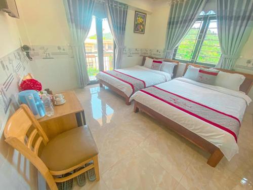 惹岛KHÁCH SẠN HƯNG THỊNH - Lý Sơn的一间卧室配有两张床、一张桌子和一张书桌