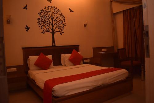 塞恩HOTEL DHIRAJ的卧室配有一张床铺,墙上挂着一棵树