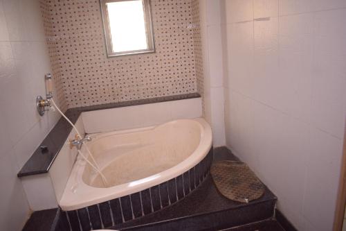 塞恩HOTEL DHIRAJ的带浴缸的浴室和窗户