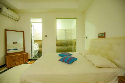 丹不拉Laaya Neem Dambulla的一间卧室配有一张带两个枕头和镜子的床