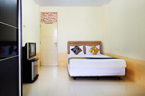 马卡萨SPOT ON 2610 Zn Guest House的一间卧室配有一张床和一台电视。
