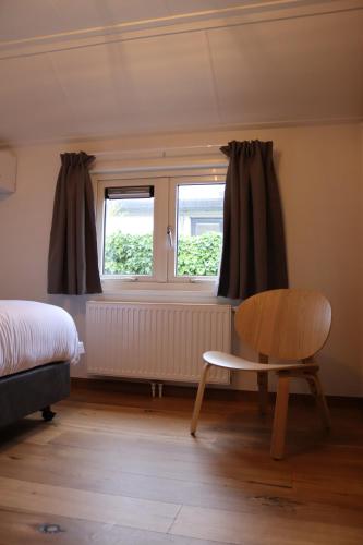 圣安娜兰Hoeve de Zeeanjelier的一间卧室设有一张床、一个窗口和一把椅子