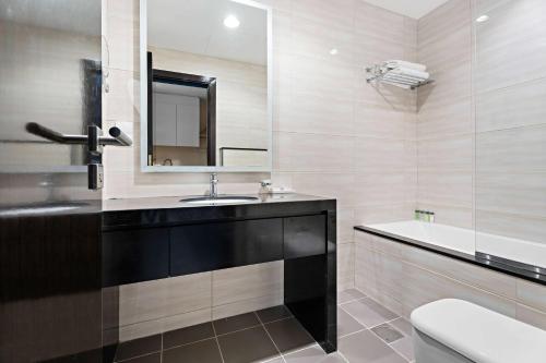 迪拜Aliving Elite Studio Celestia A Dubai South的浴室配有盥洗盆、镜子和浴缸