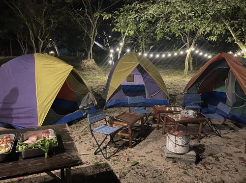 Ban Lam PiSawasdee Lagoon Camping Resort的两个帐篷和一张桌子及椅子位于泥土上