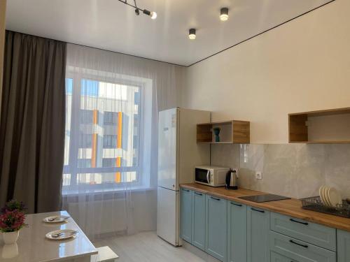 阿斯塔纳Уютная квартира в городе Астана, возле Барыс арена的厨房配有冰箱、桌子和窗户。