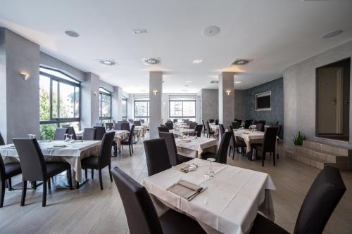 菲登扎阿索托丽亚酒店的餐厅设有白色的桌椅和窗户。