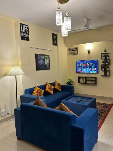 加济阿巴德Royal Ambience的客厅设有蓝色沙发,配有电视