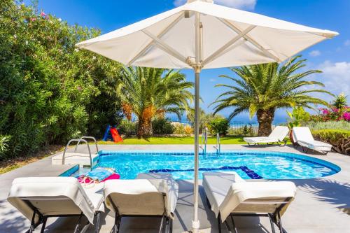 卢特拉Villa Sevos的游泳池旁的游泳池配有椅子和遮阳伞