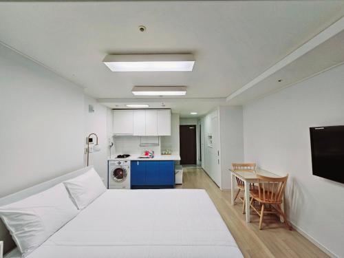 釜山Jeoung's House的一间设有白色床和一张桌子的房间和一间厨房