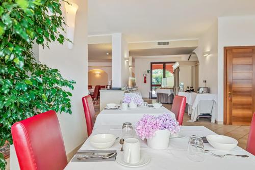 莱万托阿金图公园酒店的用餐室配有白色的桌子和红色的椅子