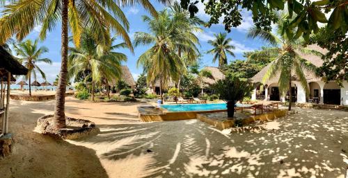 普瓦尼梅查恩加尼Mambo Ocean Resort的一个带游泳池和棕榈树的度假村