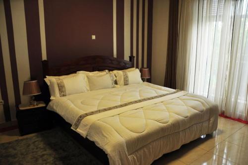 基加利VILLA MODERNE CHEZ YVONNE的卧室配有一张带白色床单和枕头的大床。