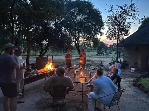 利文斯顿Sukulu Reserve的一群人坐在桌子旁,火上浇油
