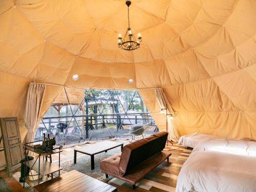 盐尻市Nagano GLAMPINGBASE enCamp的一个带一张沙发和一张桌子的帐篷的房间