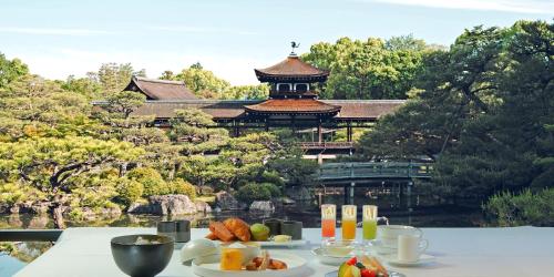 GiommachiHOTEL VMG RESORT KYOTO的一张桌子,上面有食物,后面有一座建筑