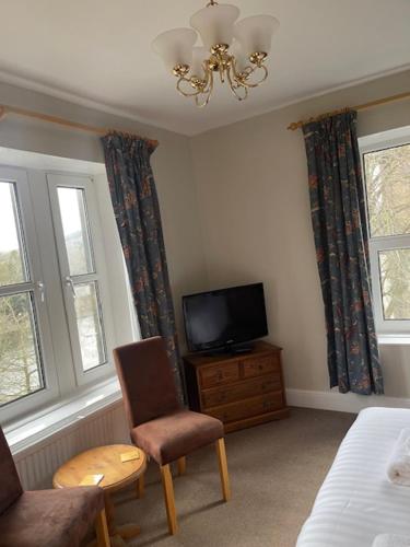 巴克斯顿威斯敏斯特酒店 的一间卧室配有电视、椅子和床