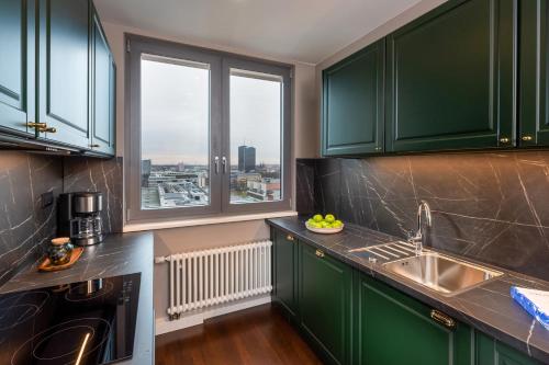柏林The Tale Luxury Suites的一个带绿色橱柜和大窗户的厨房