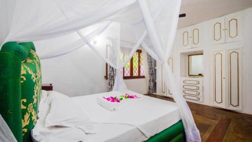 马林迪Great Rustic Escape 3 bedroom Villa, Casuarina, Malindi的卧室配有带鲜花的白色床
