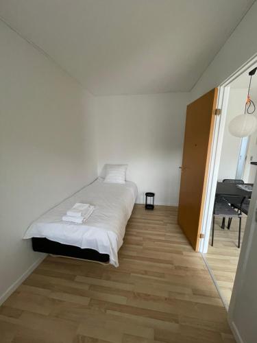 TorrigKragenæsHus的一间白色卧室,配有一张床和一架钢琴