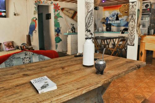 布希奥斯Raizes Surf and Bar Hostel的一张带花瓶的木桌和一本书