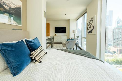 芝加哥Landing Modern Apartment with Amazing Amenities (ID634)的一间卧室配有一张带蓝色枕头的床和电视。