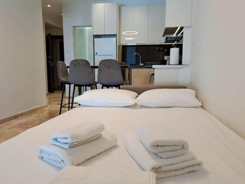 帕特雷Luxury Suite Patras (2)的一张白色的床,上面有三条毛巾