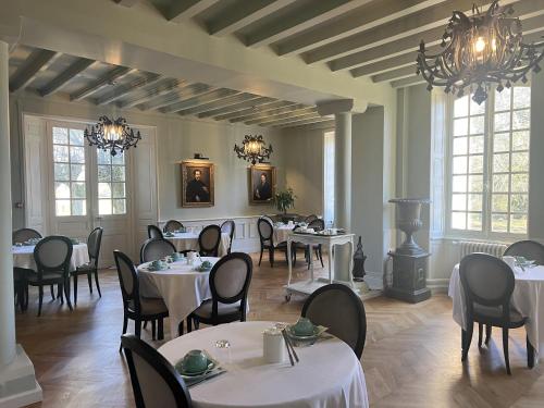BonnevalHôtel du Château du Bois-Guibert的一间设有白色桌椅和窗户的用餐室