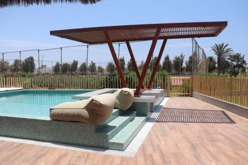 帕拉卡斯Casa Z Paracas的游泳池设有2张躺椅和1个毗邻的凉亭