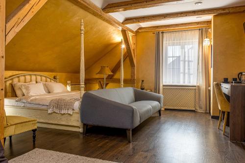 克莱佩达Kurpiai - Suites & SPA的一间卧室配有一张床、一张沙发和一个窗口
