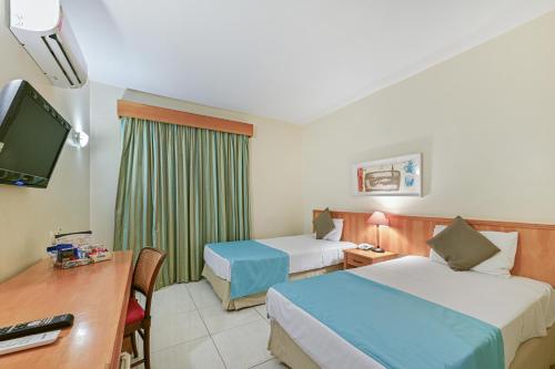 坎皮纳斯Hotel Golden Park Campinas Viracopos的酒店客房配有两张床和一张书桌