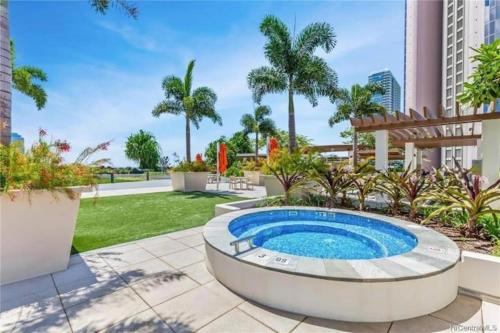 檀香山Luxury Oasis Residence的棕榈树花园内的游泳池