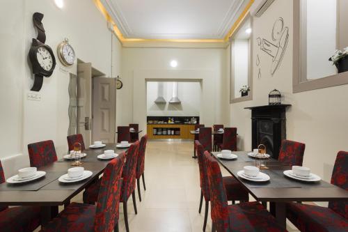 科英布拉Serenata Hotel & Hostel Coimbra的一间带桌椅和时钟的用餐室