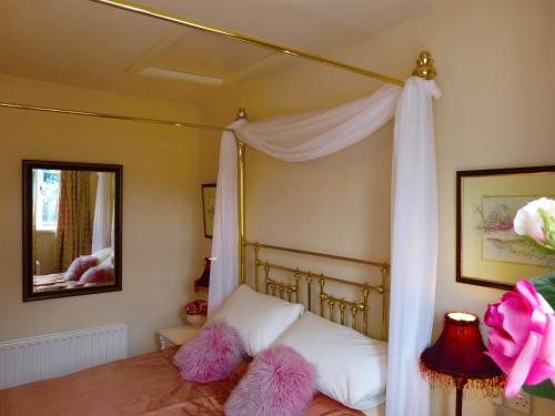 Slaithwaite伍登恩德度假屋的一间卧室配有带粉红色模糊枕头的天蓬床