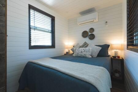 BellmeadThe Blue Ridge "Romantic" Tiny Home Near Magnolia & Baylor的一间卧室设有蓝色的床和窗户。