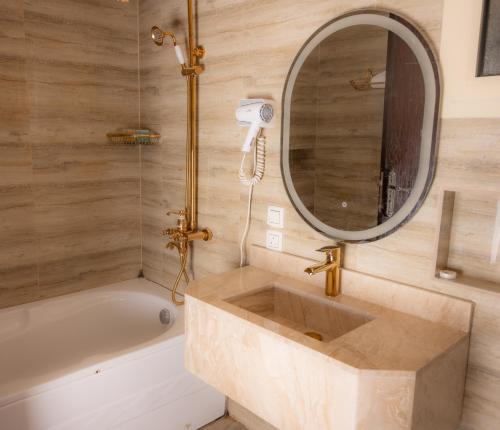 吉达Areen Hotel的一间带水槽、浴缸和镜子的浴室